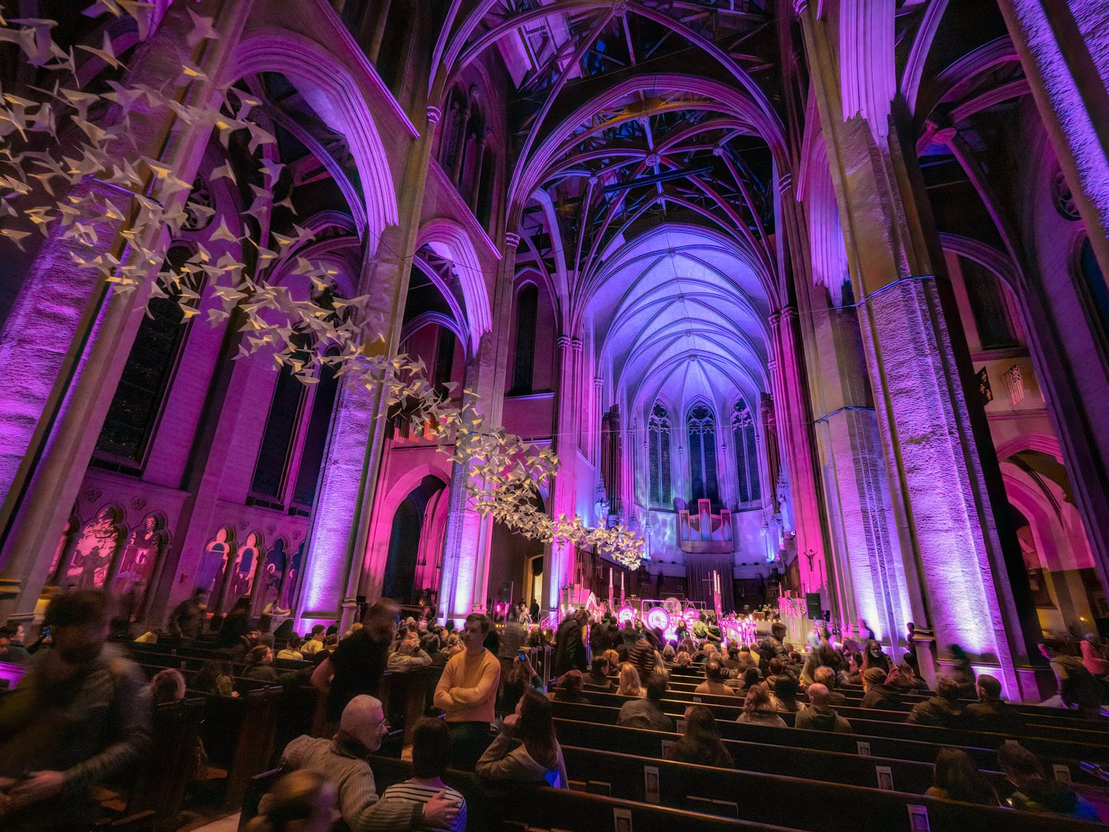Paper cranes suspended beneath glowing cathedral arches