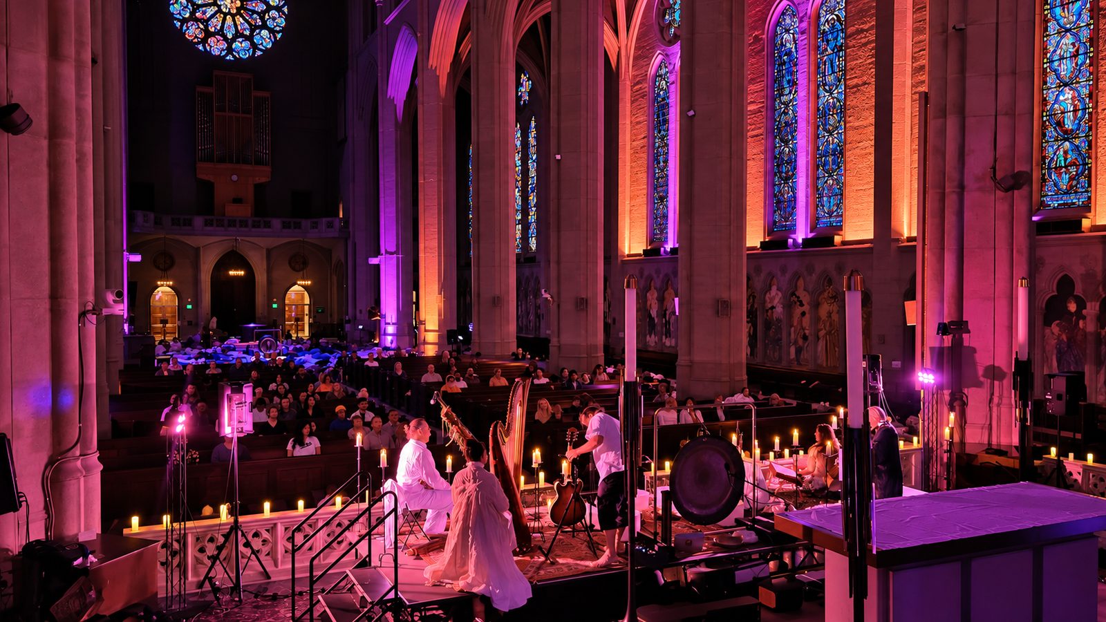 A harpist and musicians performing among candles