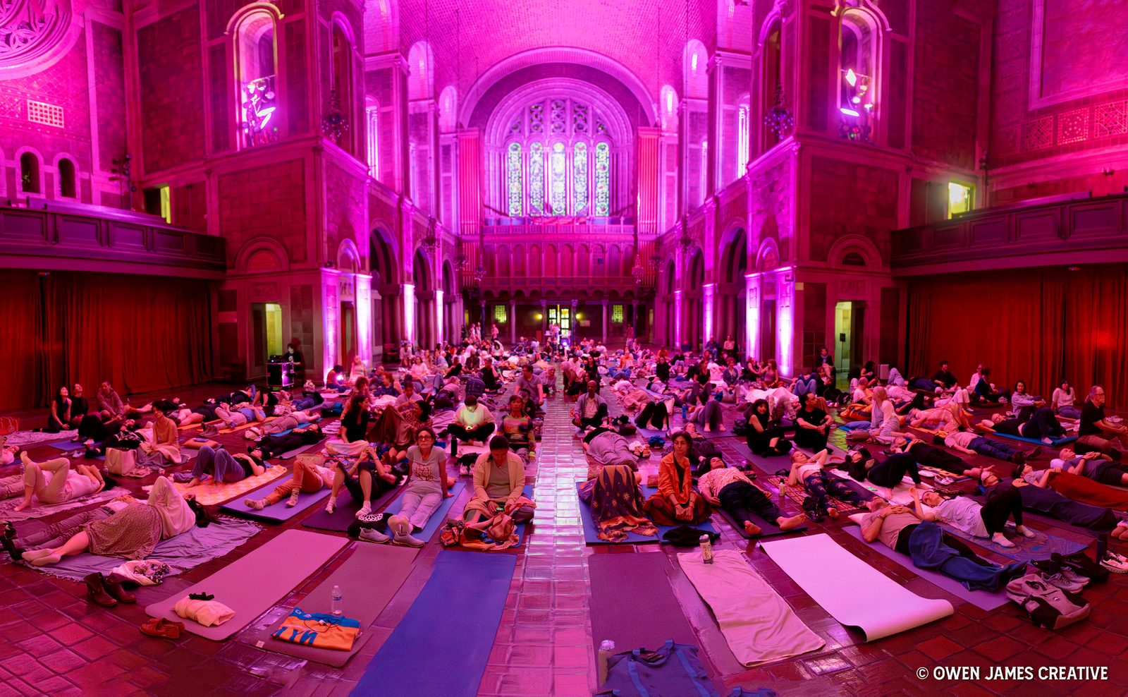 A full hall of listeners resting on mats and blankets