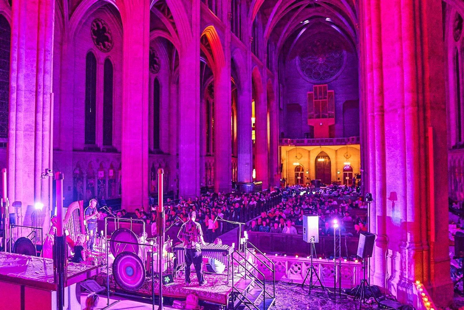Musicians with gongs and instruments at the front of a candlelit cathedral